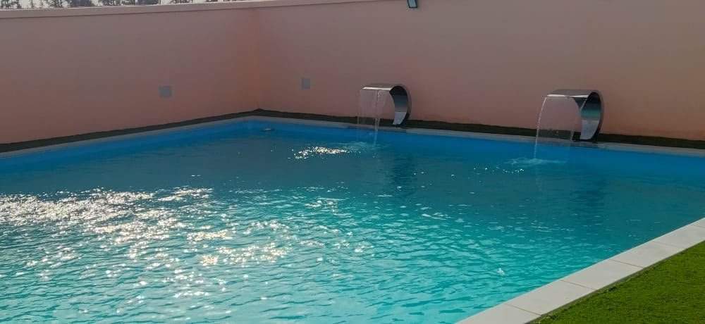 Piscine RiverPool avec deux cascades en inox et plage en gazon synthétique