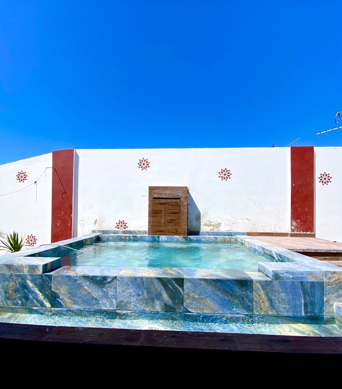 Piscine sur toit-terrasse réalisée par RiverPool : lame d'eau sur mur habillé, carrelage effet marbre bleu